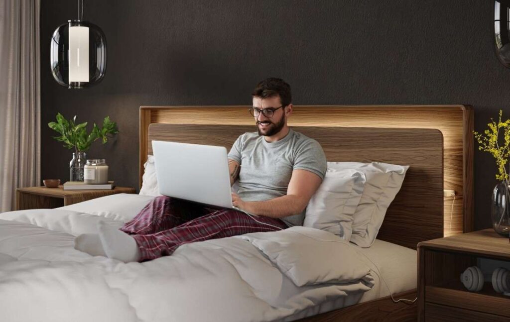 Man sitting in BDI Up Linq bed with laptop