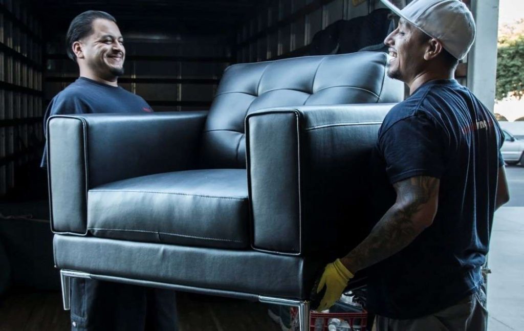 Two warehouse employees lifting a chair