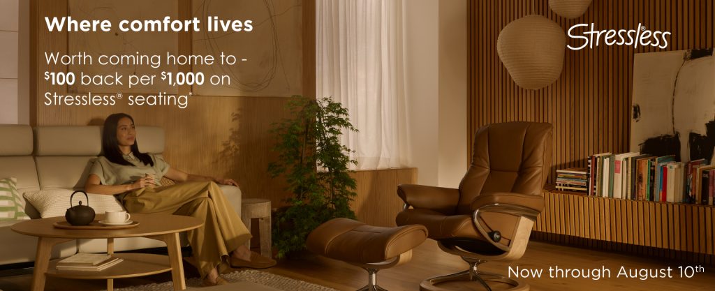 Photo of a woman relaxing in a sofa, looking up to the far top right of a living room. Previews the Stressless recliner to the right. Golden hour, mid day.