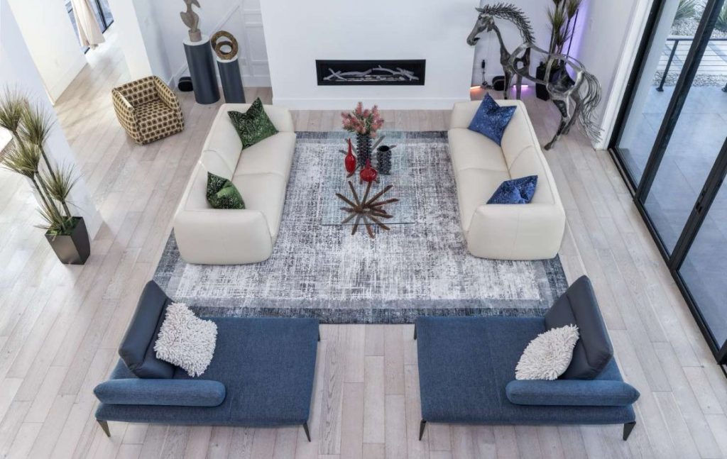 Makia living room featuring white Anzio sofas, blue Caveoso chaises, glass Atari table, & metal Walking Horse sculpture